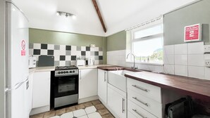 A compact kitchen with a gas stove, oven, white cabinets, a checkered backsplash, and a window with a view. - 3 bedroom accommodation in East Orchard, near Shaftesbury (East Orchard, near Shaftesbury)
