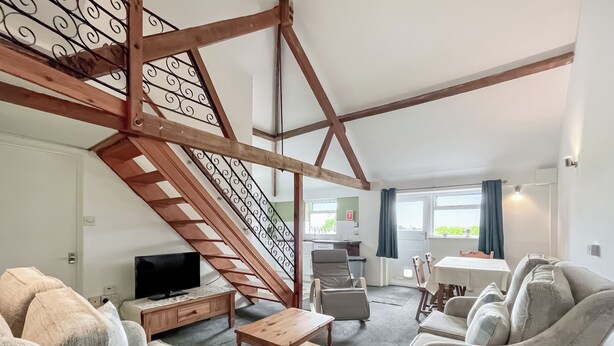 A living room with a wooden staircase, a television, and two sofas. - 3 bedroom accommodation in East Orchard, near Shaftesbury (East Orchard, near Shaftesbury)