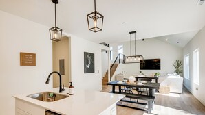 Een moderne keuken met een centraal eiland, roestvrijstalen apparatuur en hangende lampen.