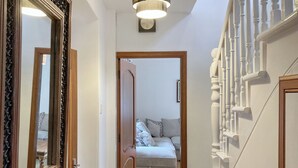 Un pasillo con una puerta de madera que da a un dormitorio con cama y mesita de noche.