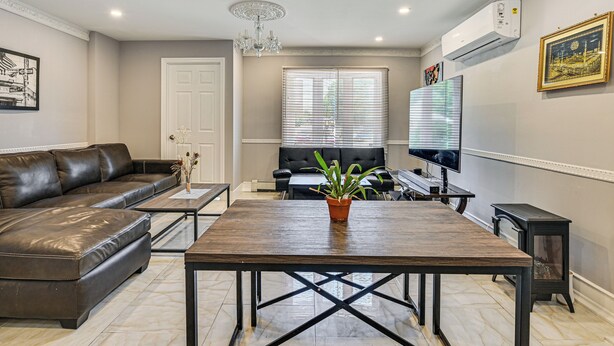 A modern living room with a leather sofa, a wooden coffee table, a TV, and a potted plant. - Pet-Friendly Valley Stream Duplex - 1 Mi to Mall! (Valley Stream)