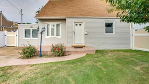 A single-story house with a front porch, a small front yard, and a garage. - Pet-Friendly Valley Stream Duplex - 1 Mi to Mall! (Valley Stream)