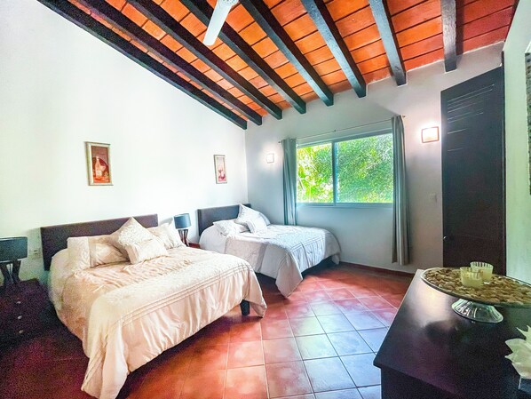Habitación de hotel con dos camas, una ventana con vistas a zonas verdes y una mesa de comedor con un plato de comida.