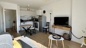 Ein kompakter Wohnbereich mit Küchenzeile, Essbereich und einem an einem Holzkasten montierten Fernseher.