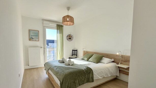 Ein Schlafzimmer mit Bett, einer Pendelleuchte, einer Heizung und einer Tür, die zu einem Außenbereich führt.