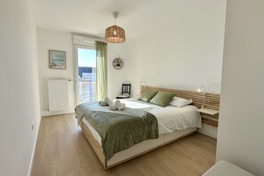 A bedroom with a bed, a hanging light fixture, a radiator, and a door leading to an outdoor area. - Henson, apartment for 4 with balcony (Saint Valery sur Somme)