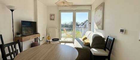 A living room with a round wooden table, a sofa, and a television.