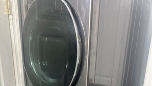 A stacked washer and dryer unit in a room with a white door and a small white table. - Cozy keys getaway  (Ramrod Key)