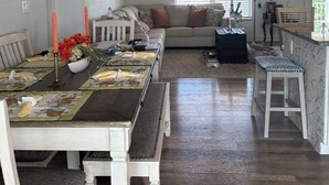 A dining area with a wooden table set for a meal, a sofa, and a kitchen area with a counter and stools. - Cozy keys getaway  (Ramrod Key)