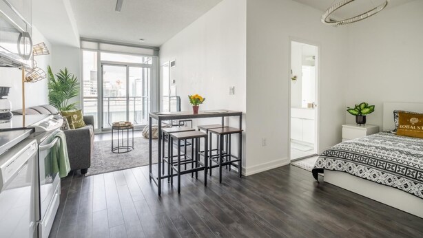 A modern apartment with a kitchen, dining area, and a bedroom.