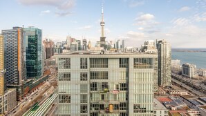 A high-rise building with a modern glass facade, located in a cityscape with a prominent tower in the background.
