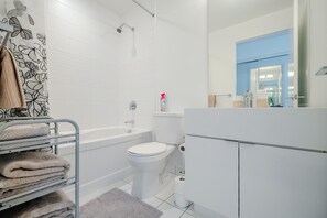 Ein modernes Badezimmer mit einer Badewanne, Toilette und einem Handtuchhalter mit gefalteten Handtüchern.