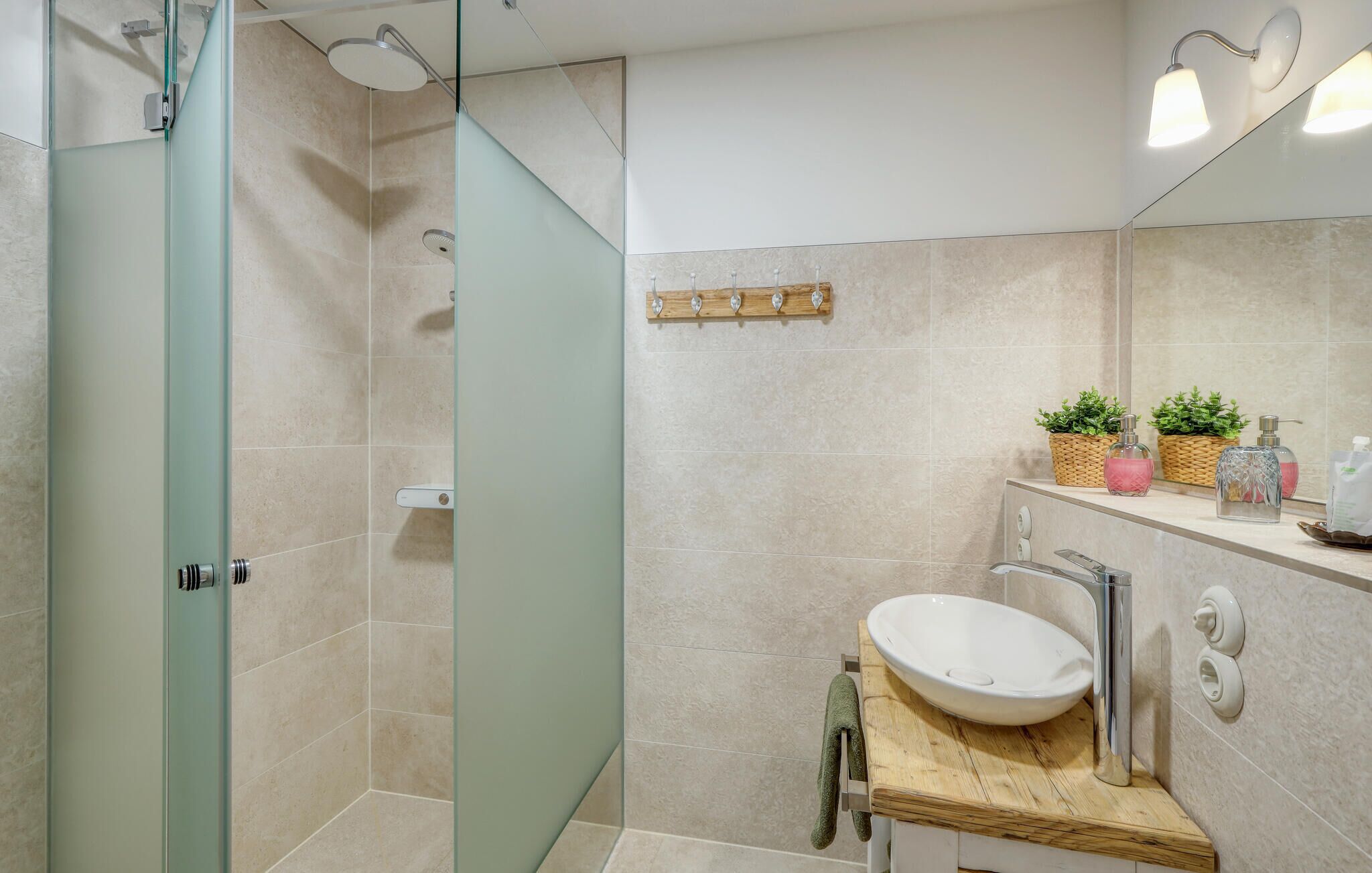 Un baño moderno con cabina de ducha de vidrio, tocador de madera y un espejo grande.