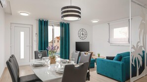 A modern living room with a dining area, teal curtains, a clock, and a TV. - 2 bedroom beautiful apartment in Podstrana (Podstrana)