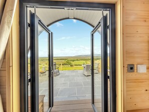 A wooden door leading to a patio with a view of a grassy landscape and a stone floor. - 1 bedroom accommodation in Talybont, near Borth (Talybont, near Borth)