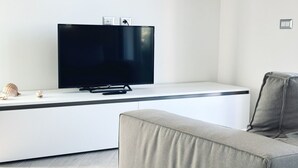 Una sala de estar moderna con televisor de pantalla plana, un sofá y un diseño minimalista.