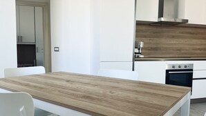 Una cocina moderna con armarios blancos, encimera de madera y campana extractora de acero inoxidable.