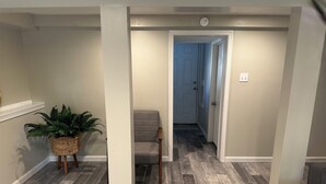 A hallway with a wooden floor, a grey upholstered chair, and a potted plant. - Charming 3-bedroom house with AC, WiFi in fabulous Bethlehem (Bethlehem)