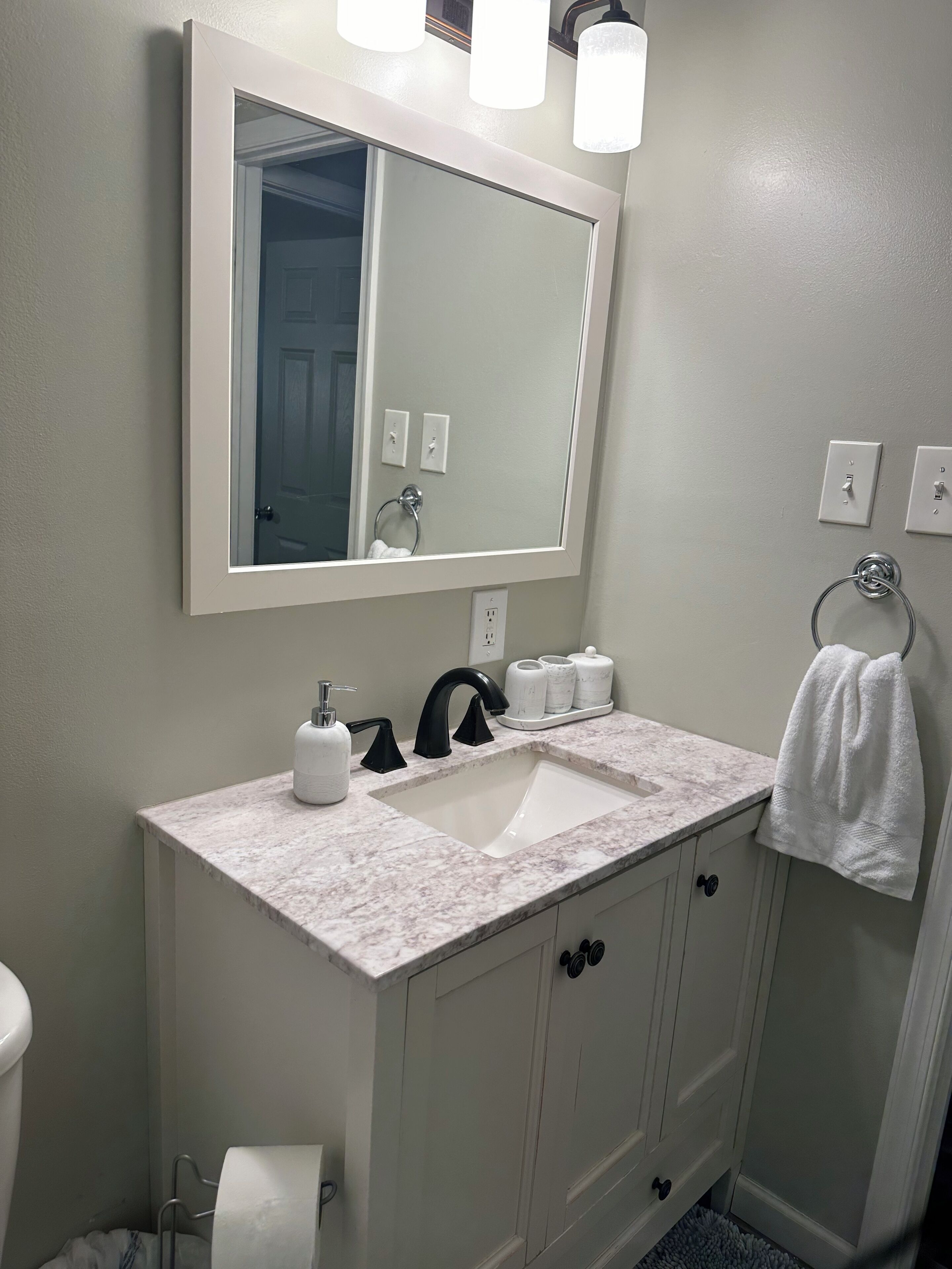 A bathroom with a white sink, a large mirror, and a towel hanging on a rack.