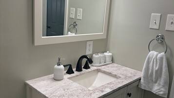 A bathroom with a white sink, a large mirror, and a towel hanging on a rack.
