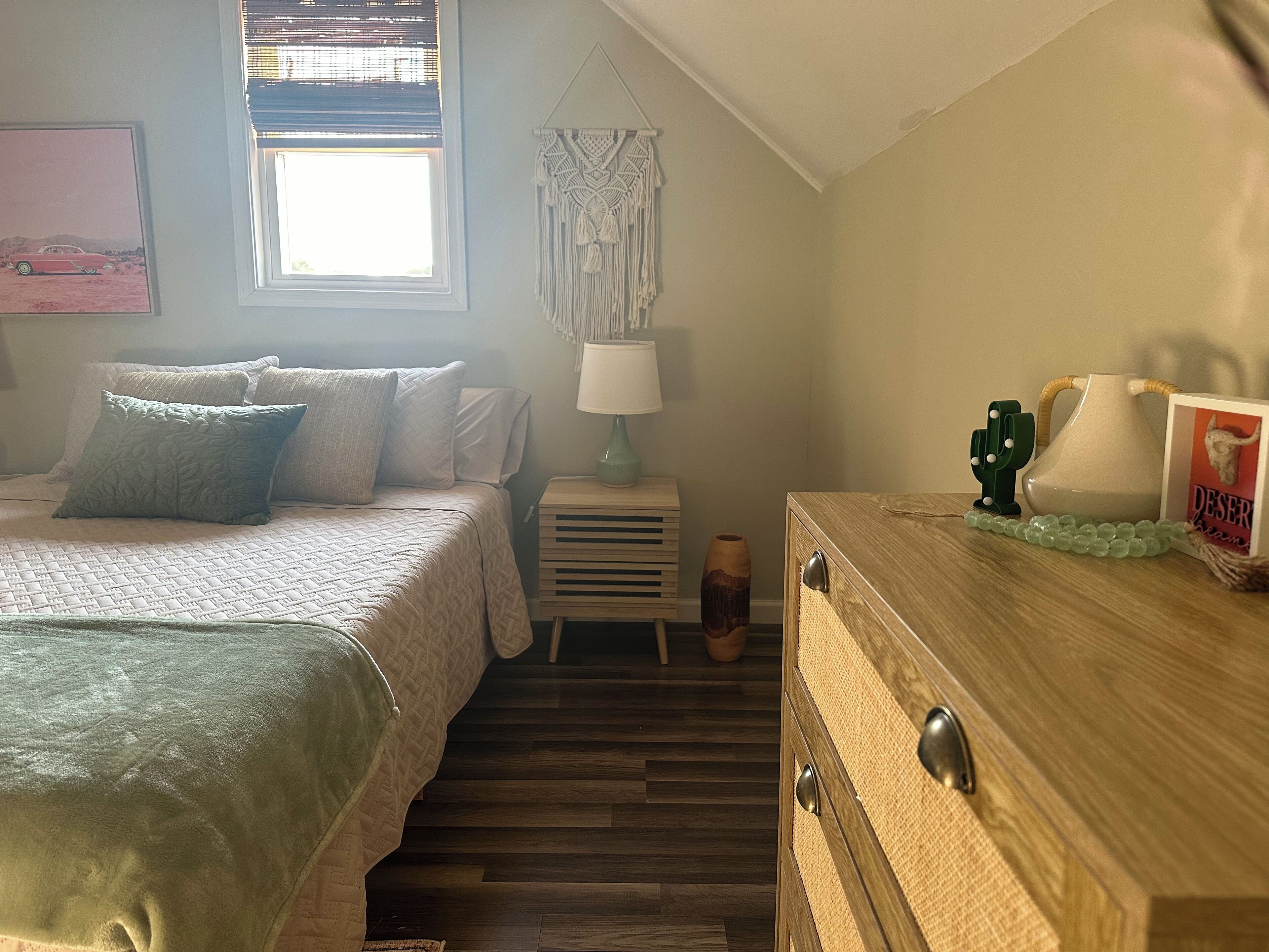 A bedroom with a bed, bedside table, lamp, and decorative items.