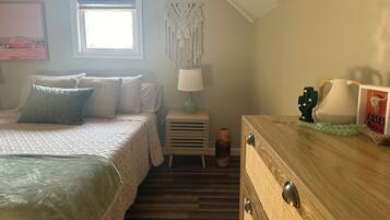 A bedroom with a bed, bedside table, lamp, and decorative items.