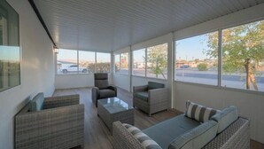 Un salon moderne avec des meubles en osier, de grandes fenêtres et une vue sur la rue.