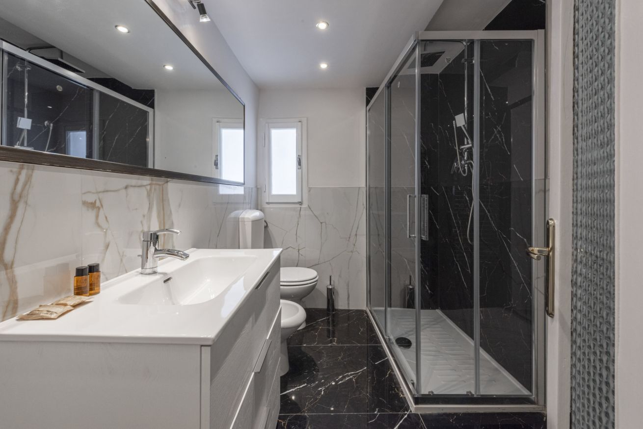 Een moderne badkamer met een dubbele wastafel, toilet en douchecabine.