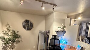 Quarto com escrivaninha, cadeira, planta em vaso e janela com design geométrico.