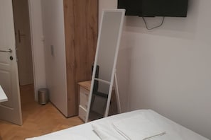 A room with a bed, a wardrobe, a mirror, and a television mounted on the wall. - Shining Room in Shared Apt.- Ideal for Long Stays (Vienna)