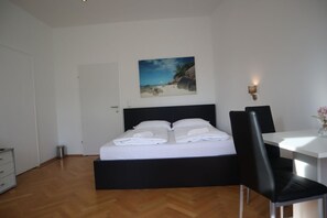 A bedroom with a bed, a desk, a chair, a painting, and a wall-mounted light fixture. - Cozy 1BR@ Apt. In Prime Location of Vienna (Vienna)