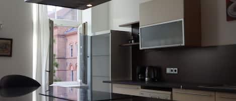 Una cocina moderna con una isla grande, electrodomésticos integrados y vistas a un edificio de ladrillo.