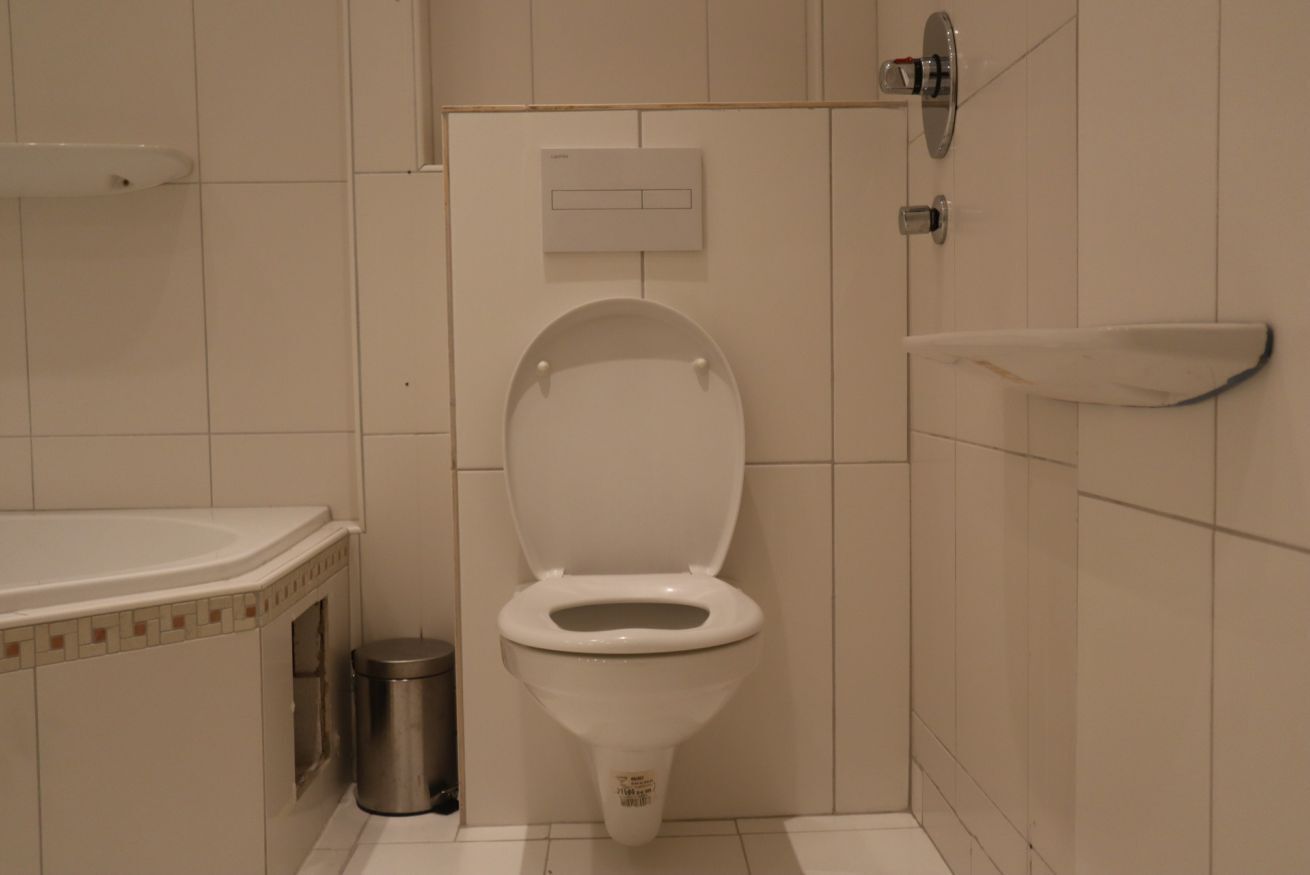 Een badkamer met toilet, prullenbak en wastafel.