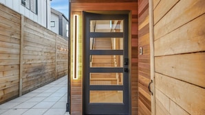 A modern wooden door with a glass panel and a vertical light strip. - Comfortable Home in the Heart of West Seattle (Seattle)