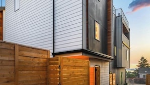 A modern two-story house with a sloped roof, a wooden fence, and a paved driveway. - Comfortable Home in the Heart of West Seattle (Seattle)