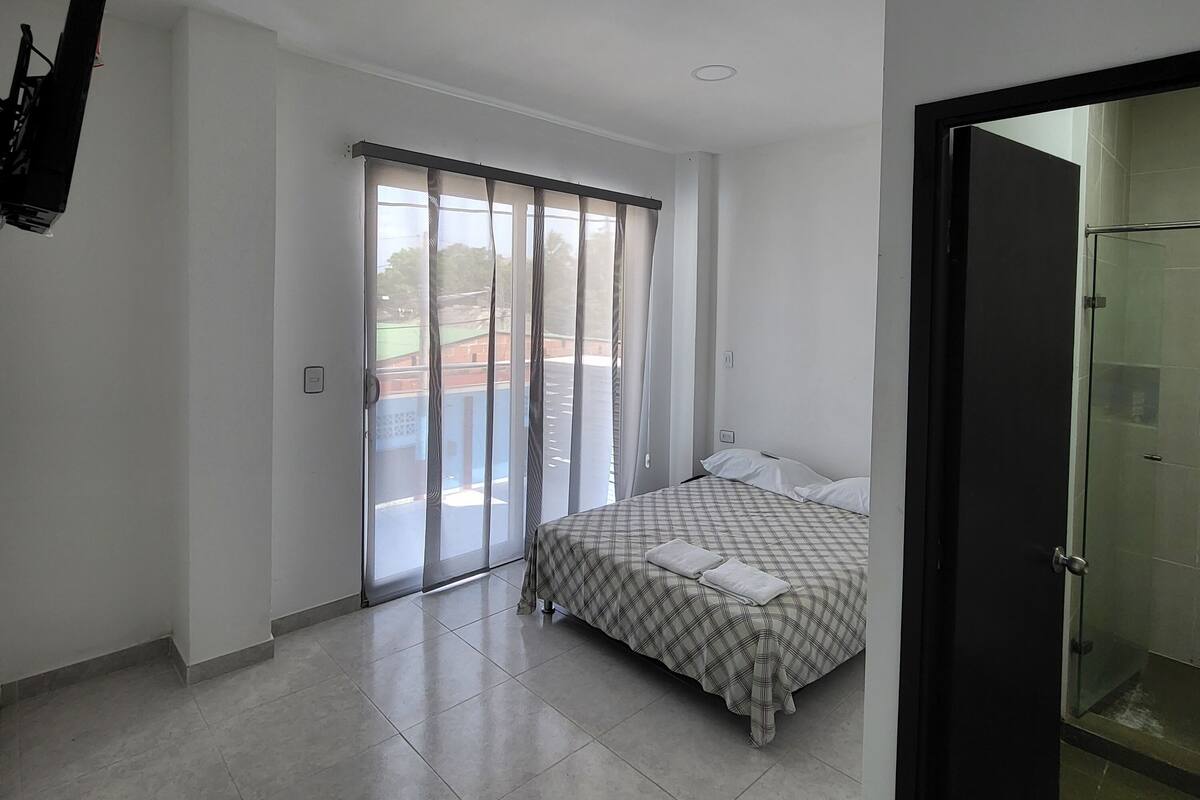 Ein Schlafzimmer mit Bett, einer Schiebetür zum Balkon und einer Duschkabine.