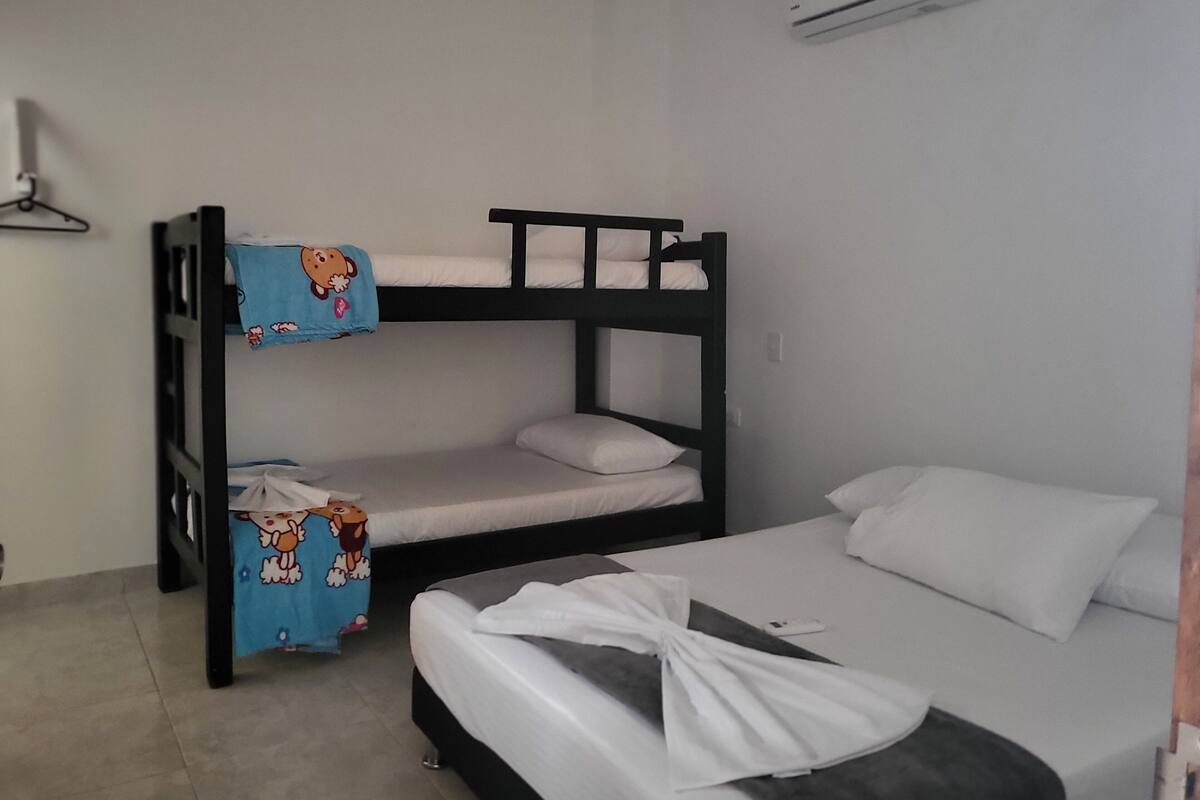 Ein Mehrbettzimmer mit einem Einzelbett und einer Klimaanlage an der Wand.