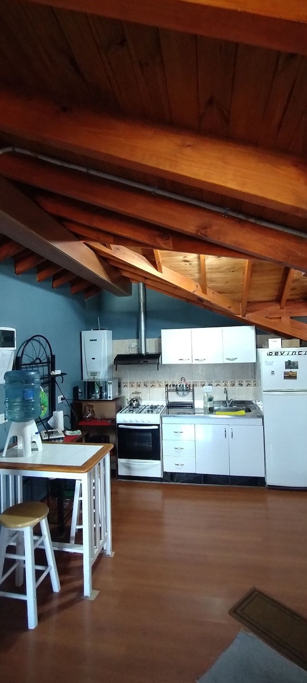 A kitchen with wooden beams, white cabinets, a stove, and a water dispenser.