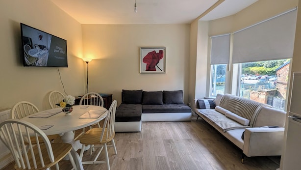 A modern living room with a dining table, a sofa, and a couch. There is a painting on the wall and a lamp. - 2 Bedroom flat in Manchester. Close to city centre and Heaton Park.  (Salford)