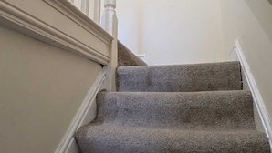 A staircase with carpeted steps and white balusters. - 2 Bedroom flat in Manchester. Close to city centre and Heaton Park.  (Salford)