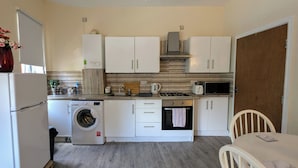 A compact kitchen with a washing machine, microwave, and oven. - 2 Bedroom flat in Manchester. Close to city centre and Heaton Park.  (Salford)