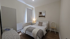 A bedroom with a bed, bedside table, lamp, chair, radiator, and a window. - 2 Bedroom flat in Manchester. Close to city centre and Heaton Park.  (Salford)