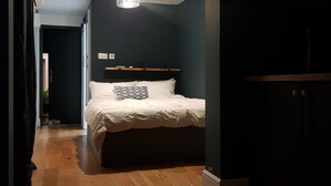 Une chambre à coucher avec un lit, un luminaire suspendu et un plancher en bois.