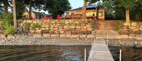 A dock extending into a calm body of water, surrounded by a stone wall and trees.