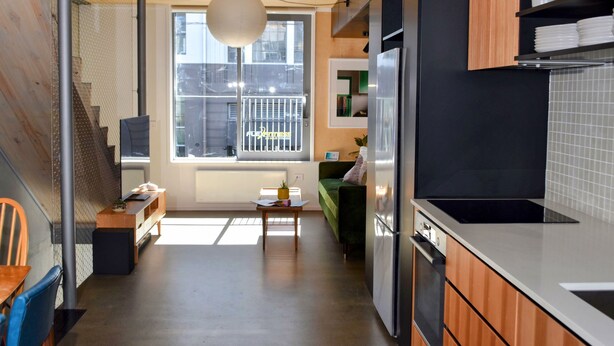 A modern kitchen with a built-in oven, a refrigerator, and a dining area with a table and chairs. - Luxury CBD townhouse 3 bed | 3 bath | 4 bed (Wellington)