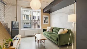 A modern living room with a green sofa, wooden coffee table, and a hanging light fixture.