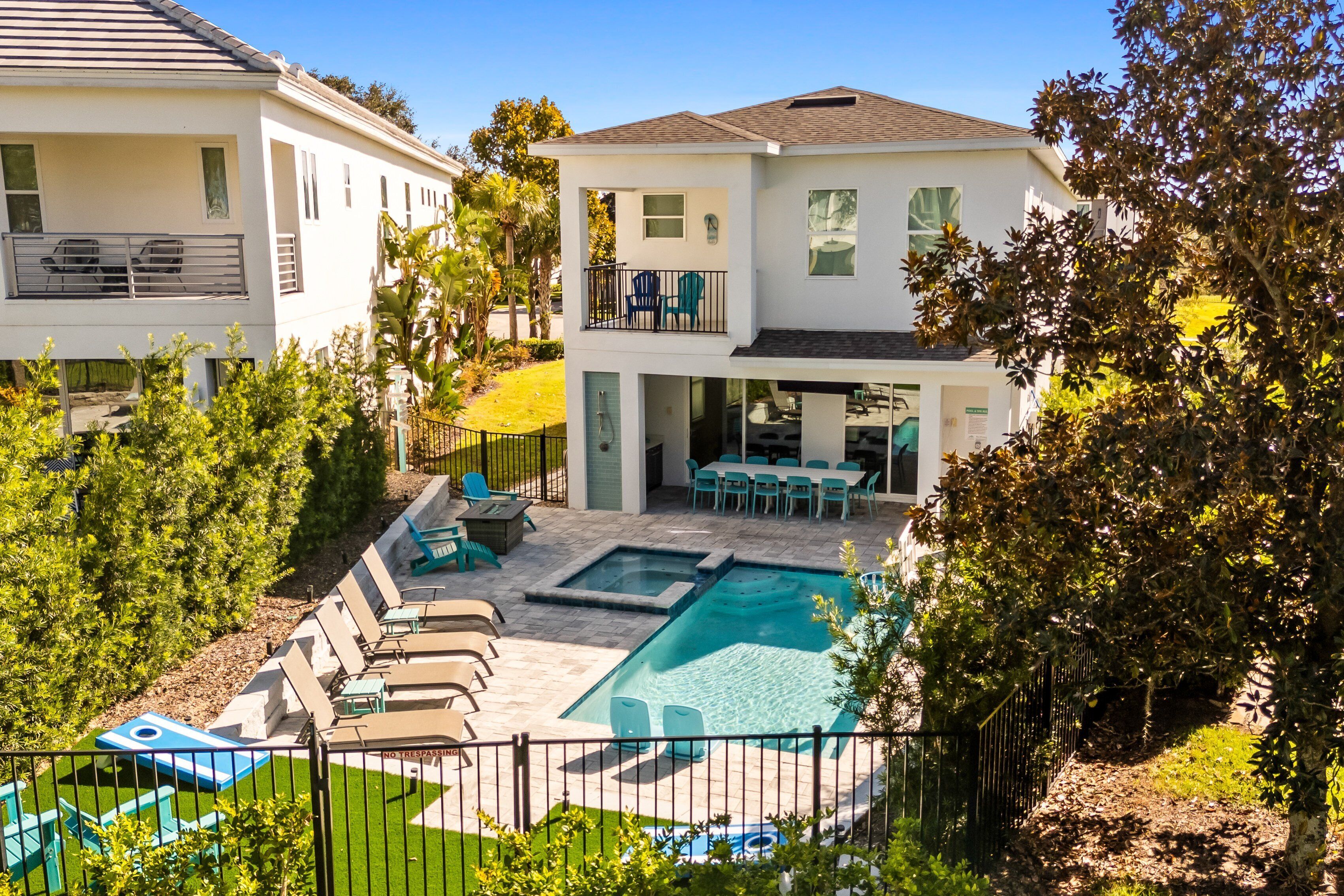 A two-story house with a swimming pool, outdoor seating, and a fenced backyard.