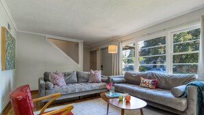 Ein Wohnzimmer mit grauem Sofa, rotem Sessel und einem kleinen Couchtisch mit Dekoration.