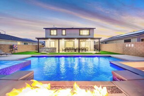 A modern two-story house with a swimming pool, outdoor seating, and a fire pit.