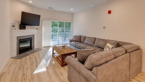 Un salon moderne avec une cheminée, un grand canapé et un téléviseur à écran plat fixé au mur, juste au-dessus du canapé.